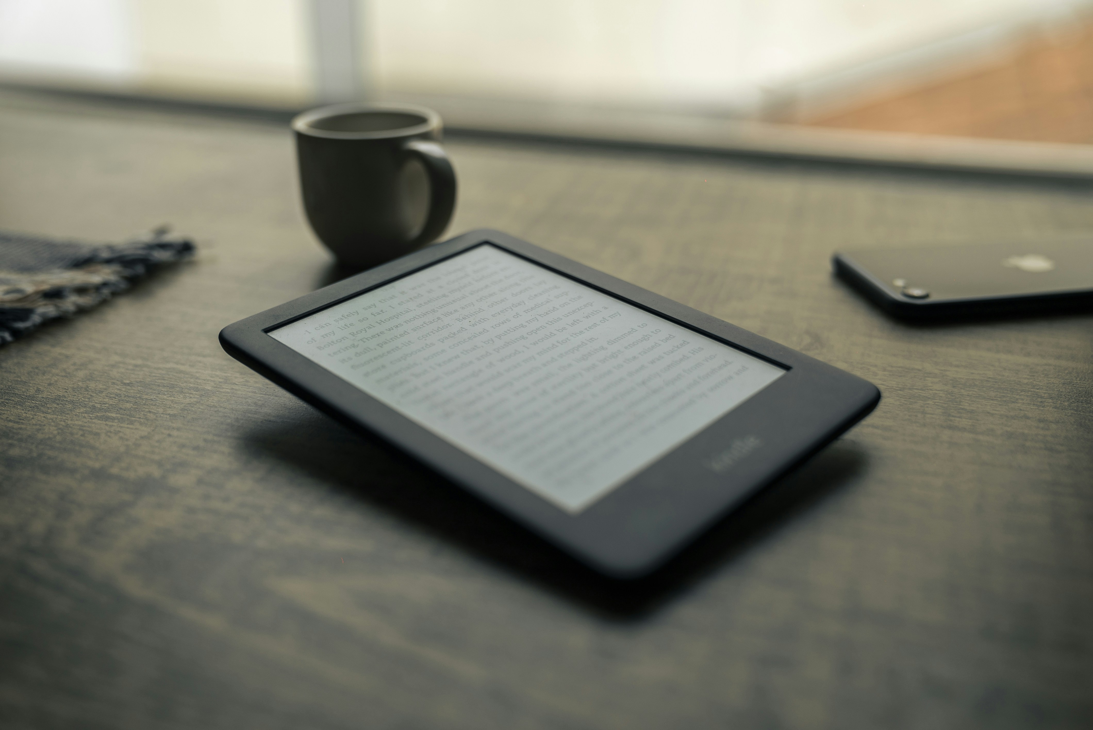 black android smartphone beside black ceramic mug on brown wooden table